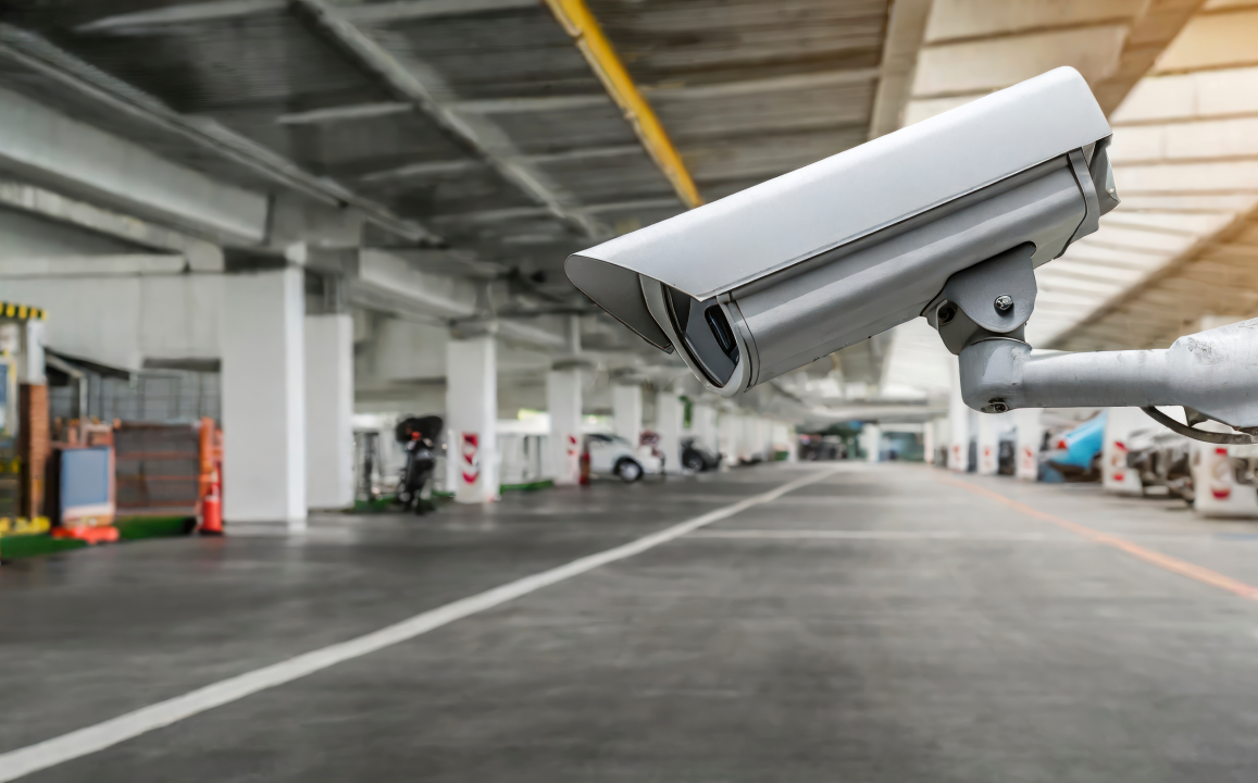 Камера видеонаблюдения на стойке в помещении автосервиса, контролирующая зону обслуживания автомобилей и мотоциклов.